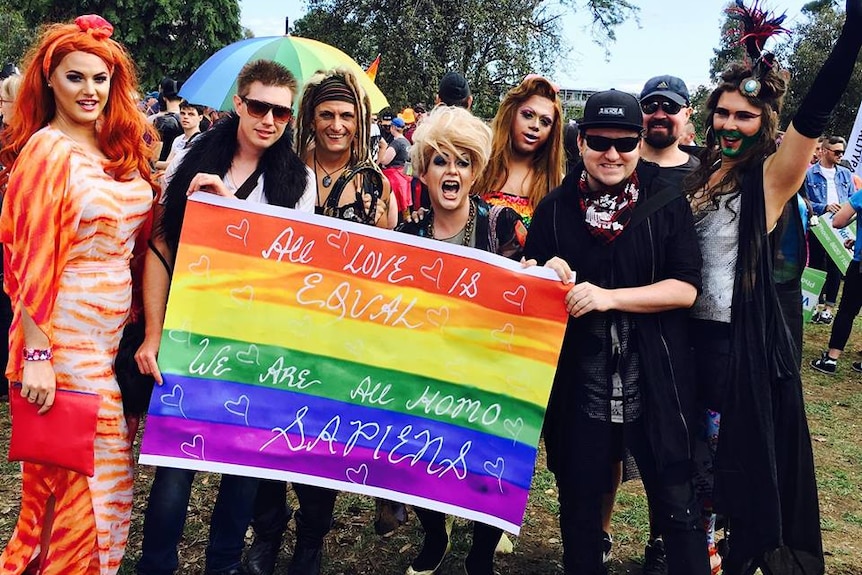 Ben Jago and others hold a large rainbow flag.