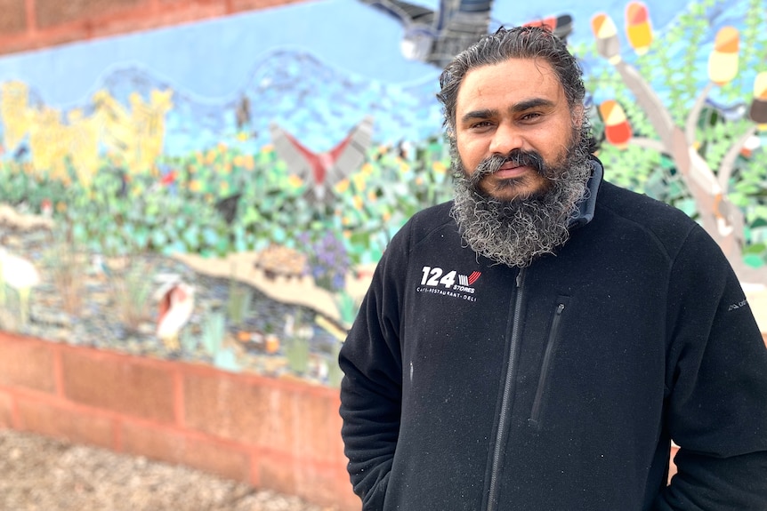 a man stands in front of a mural