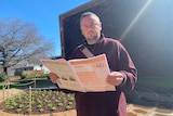 A man holds the 2021 census paper and is frowning 