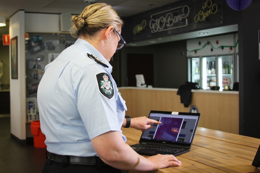 woman in uniform points to laptop screen
