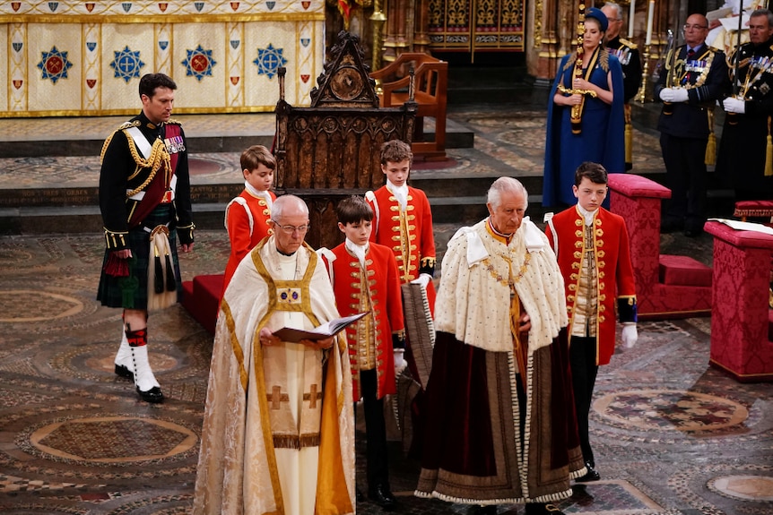 King Charles walks down the aisle in Westminster Abbey, four young boys carry the train of his robe