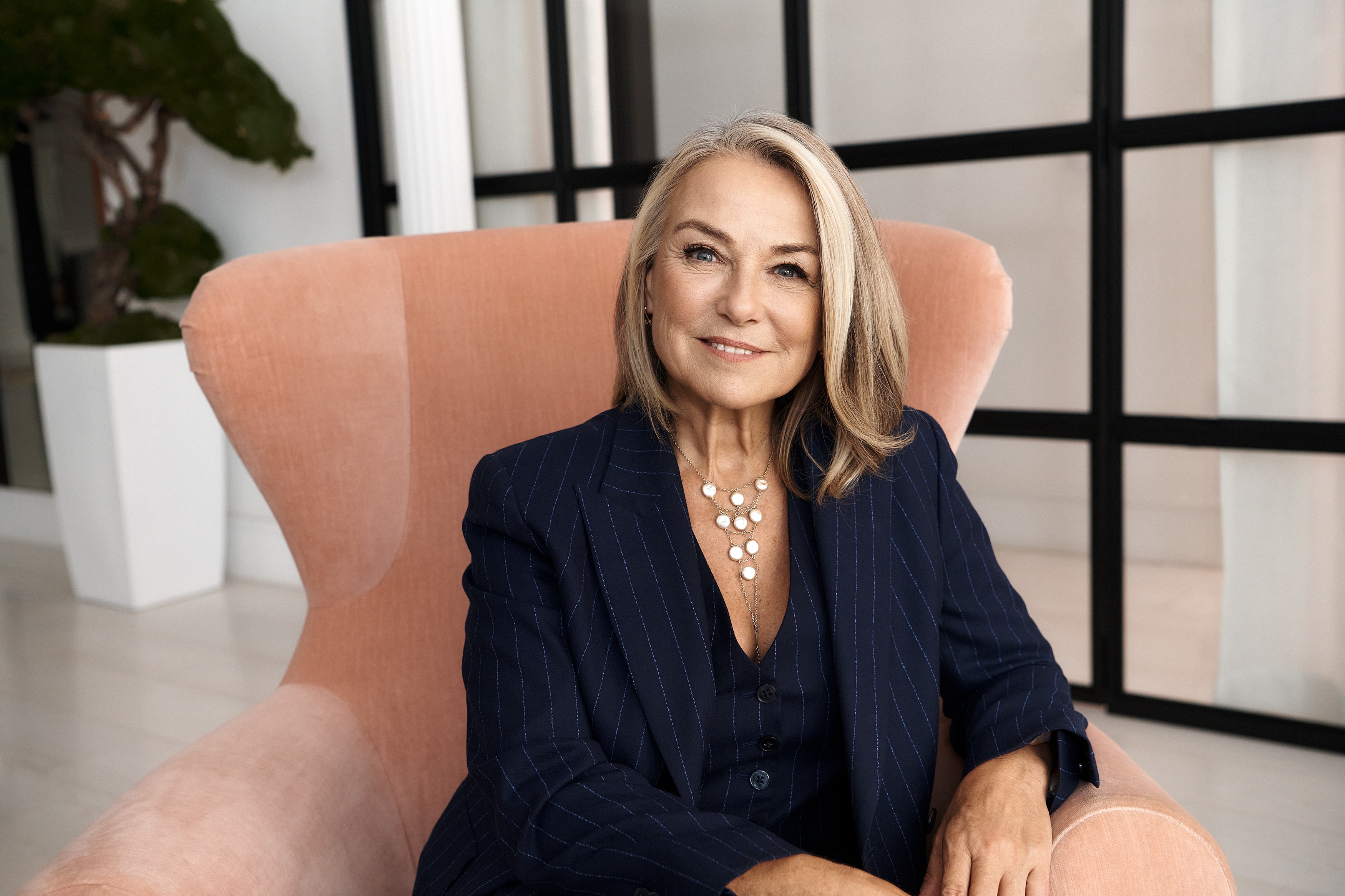 Esther Perel sits in a wing back chair and is smiling at the camera