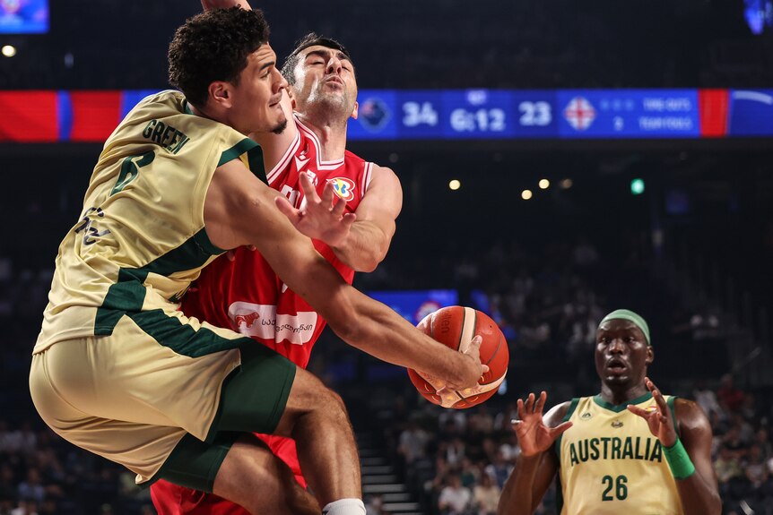 Josh Green passes around a defender to Duop Reath during a game between Australia and Georgia at the FIBA World Cup.