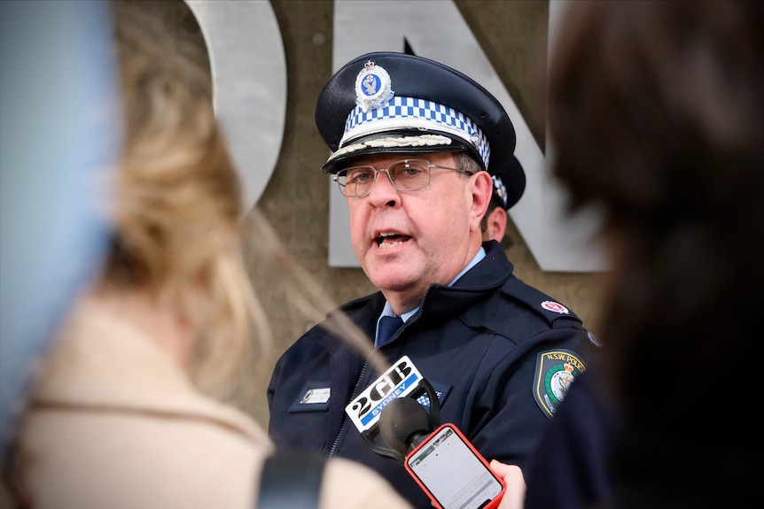 A senior male leader of the NSW Police force gives a press conference outside a police station