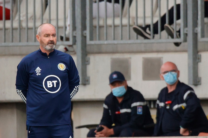 Steve Clarke stands with his hands behind his back