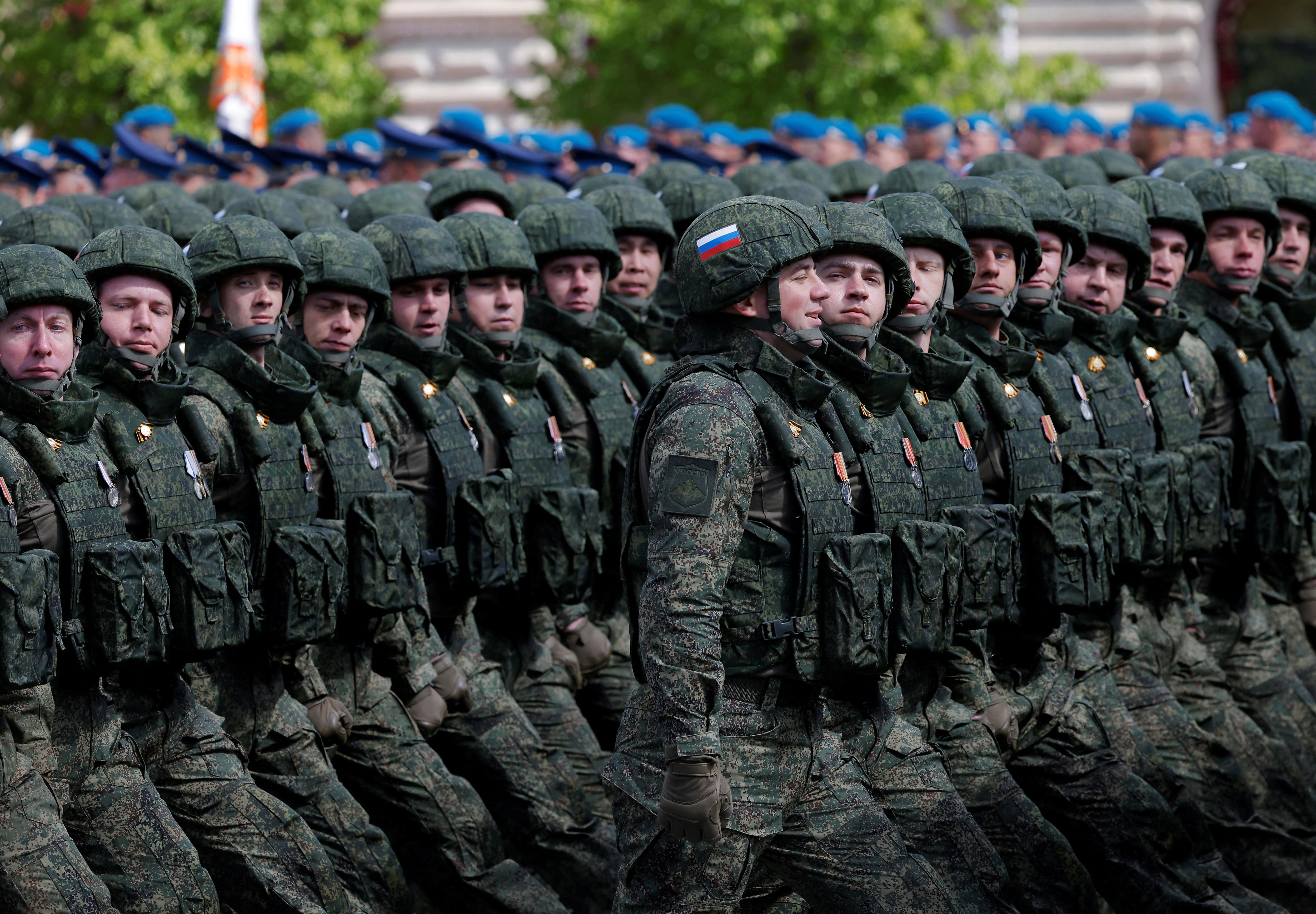 Dozens of Russian soldiers in green uniforms and helmets marching in neat rows.