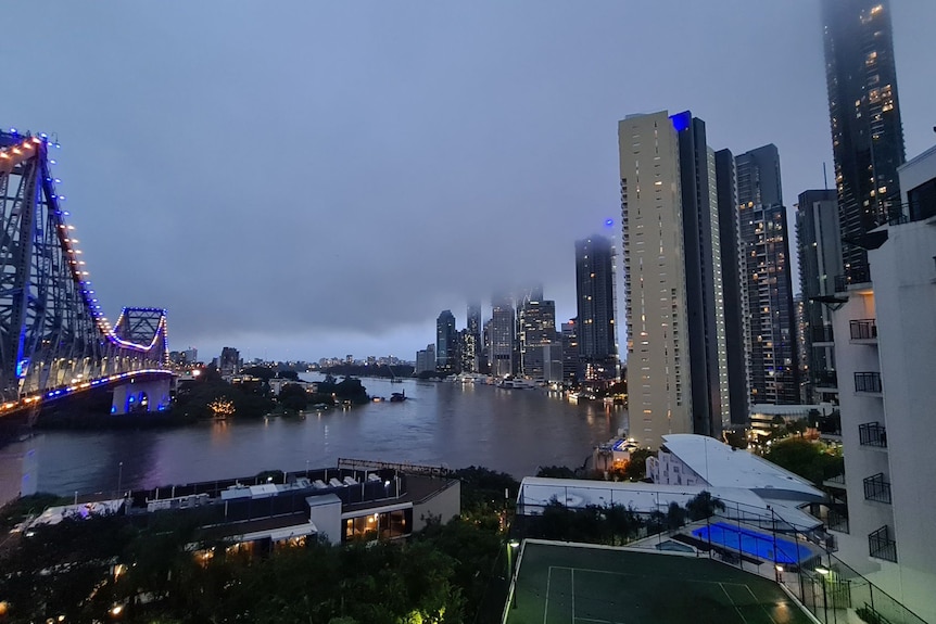 Flooded Brisbane River in flood at dusk with river fill of brown water and low hanging cloud