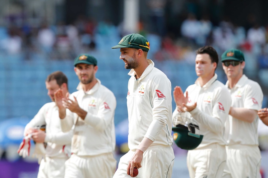 Australian players clap Nathan Lyon as they leave the field.