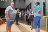 Police speak with four Indigenous people on the steps of MG Corporation's Kununurra office