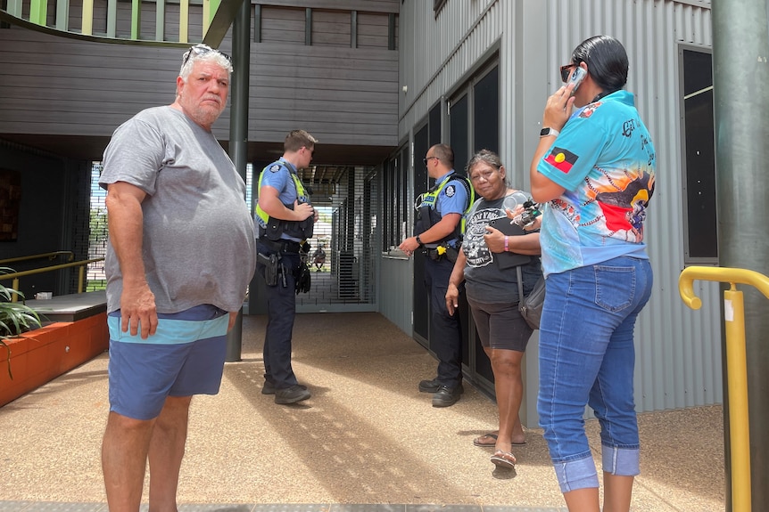 Police speak with four Indigenous people on the steps of MG Corporation's Kununurra office