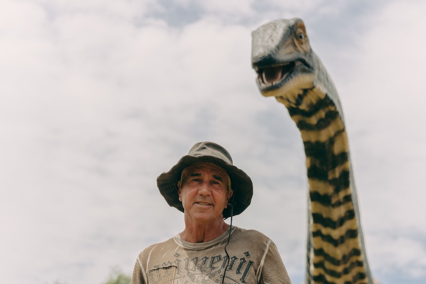 A man standing next to a life-sized dinosaur model