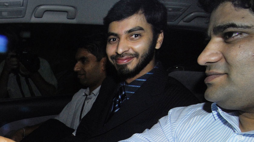 Flown home: Mohamed Haneef (with beard) smiles as he arrives at Brisbane Airport to fly home to India last night.