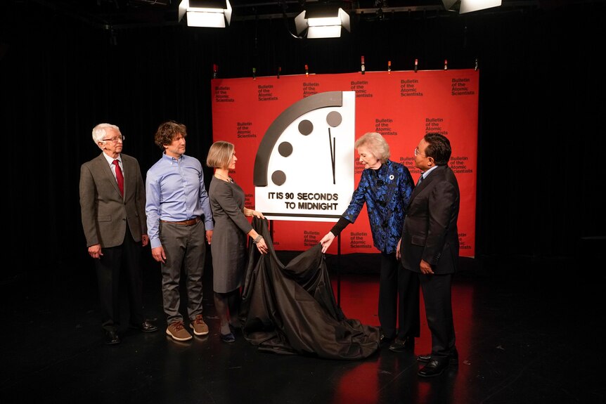 A group of people remove a cloth from a clock.