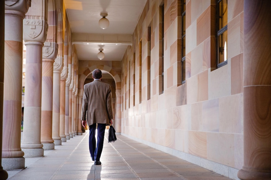Ian Frazer walks along a corridor at the University of Queensland