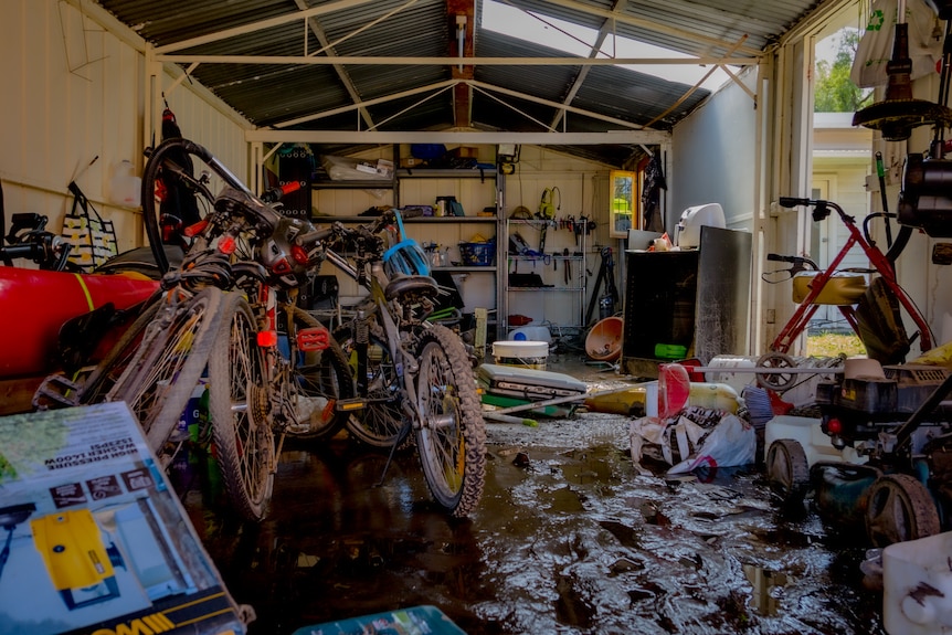 A garage filled with bikes and equipment covered in mud