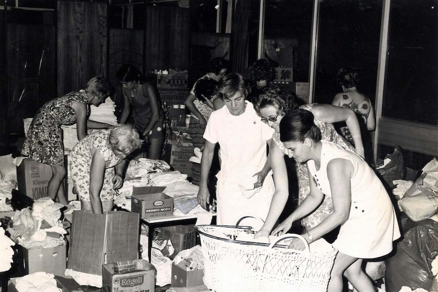 Clothes are sorted while a mother looks after a baby in a basket