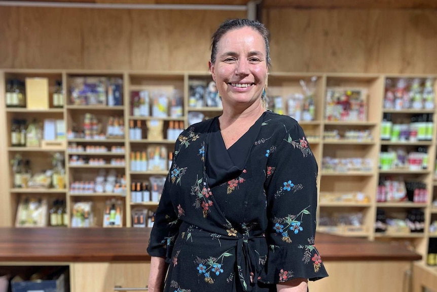 A woman stands in front of shelves of packaged honey