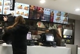 A young woman smashes equipment inside a KFC.