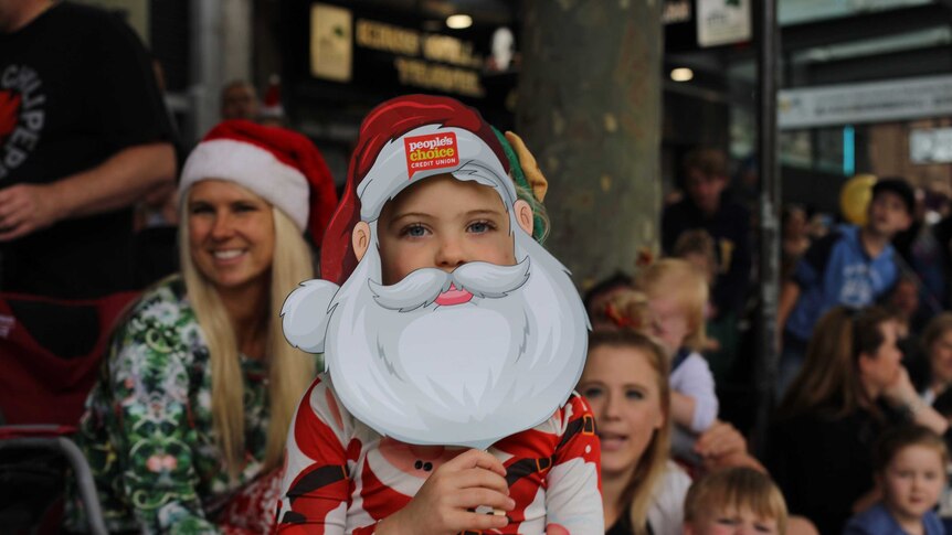 A child wearing a Santa mask at the pageant