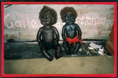 Two black dolls lean up against a wall