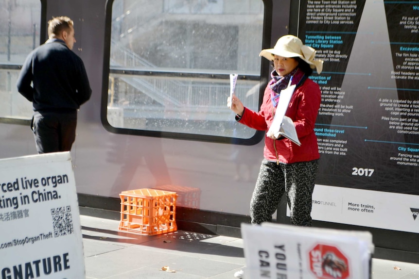 Woman in white hat holds pamphlets.