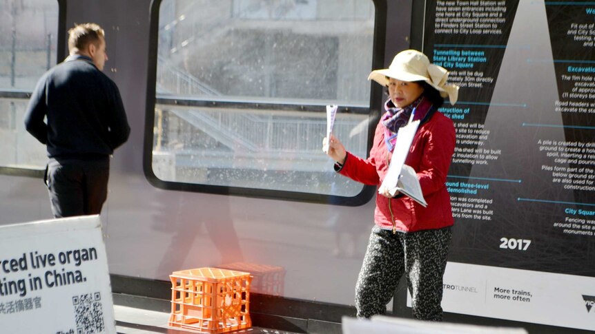 Woman in white hat holds pamphlets.