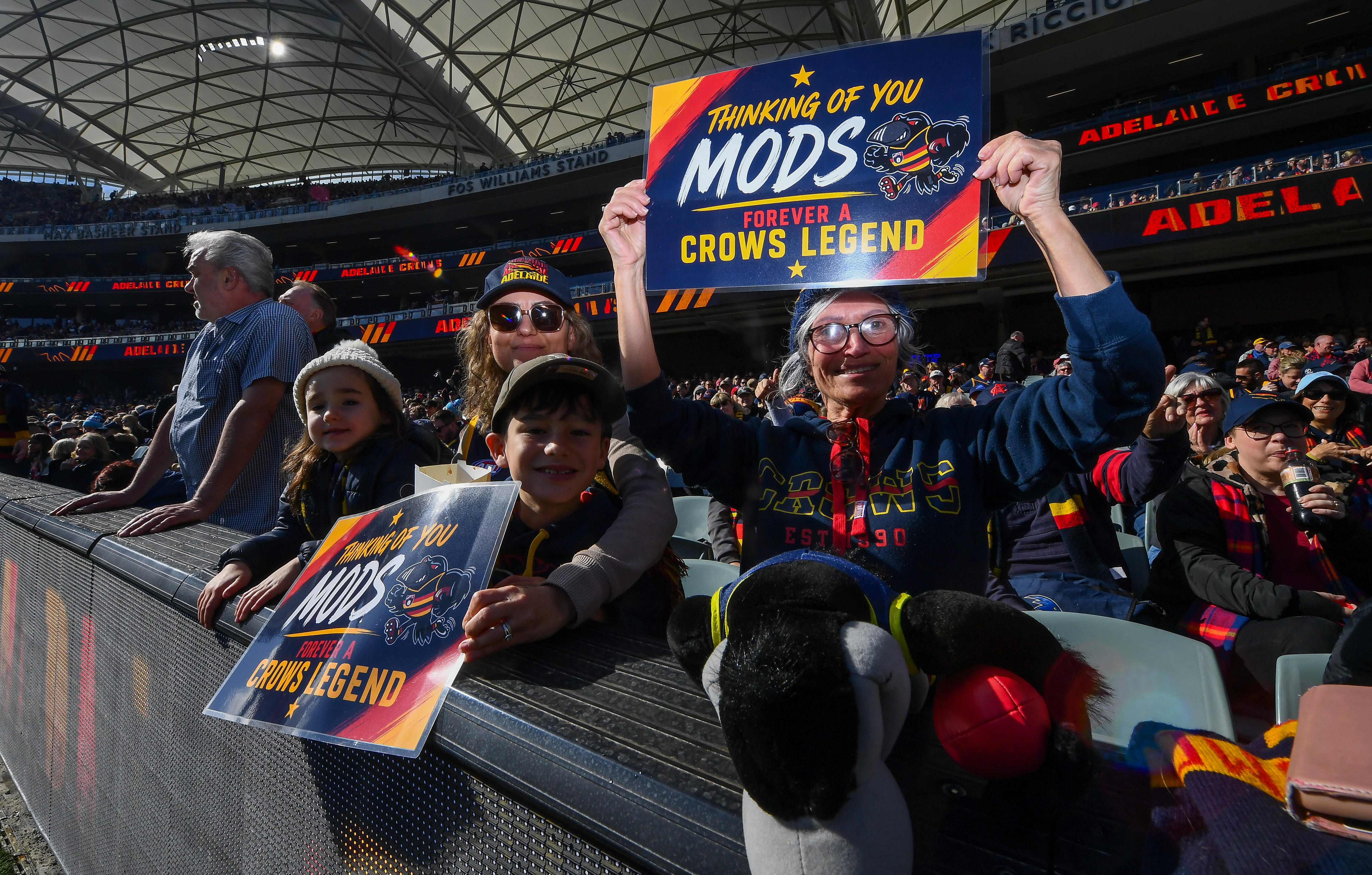 Adelaide Crows supporters hold a sign saying THINKING OF YOU MODS CROWS LEGEND