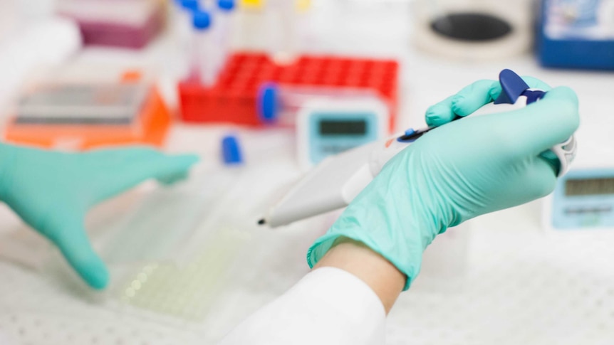 A scientist's hand holds science equipment in a laboratory