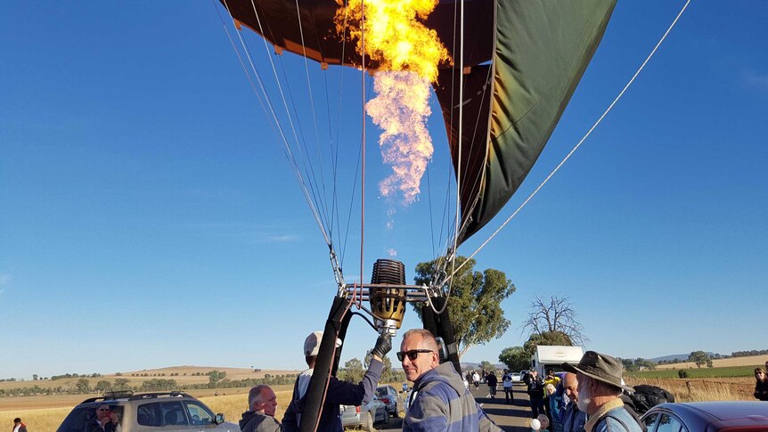A hot air balloon lands on a rural road.