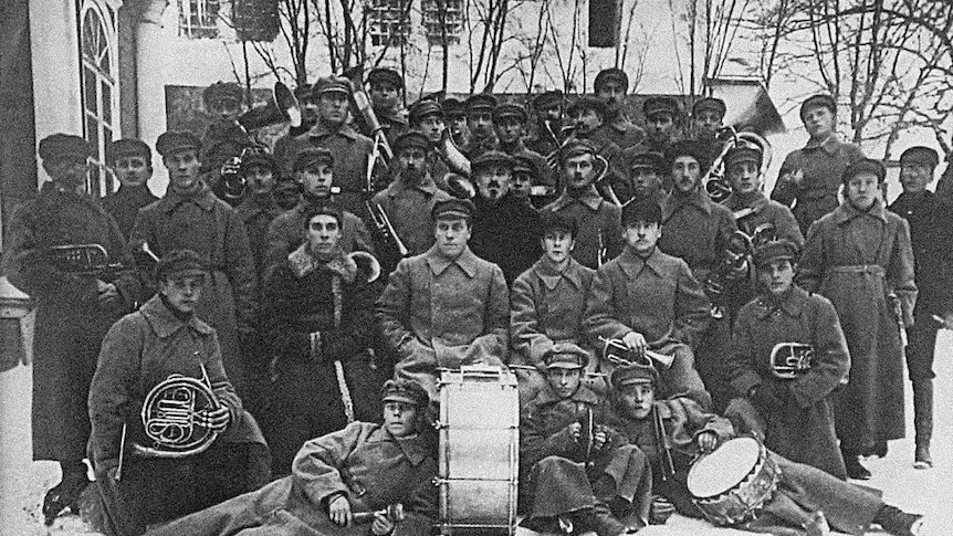 the prison camp band - men in big overcoats  + warm hats outside in a Russian winter pose with their instruments.