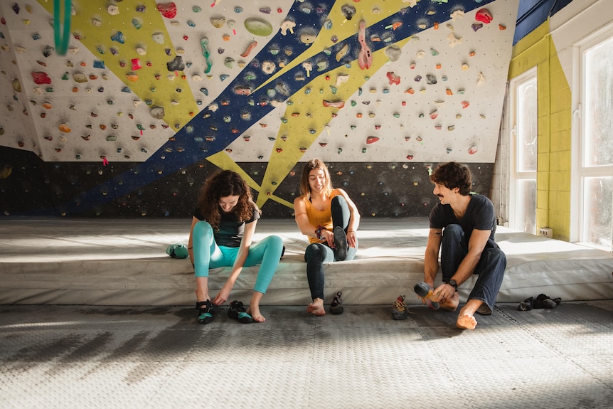 group of young people preparing to climb putting on shoes to climb in indoor boulder