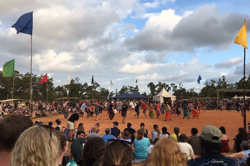 Traditional dancers in modern dress in Arnhem Land are surrounded by a circle of onlookers at the Garma Festival