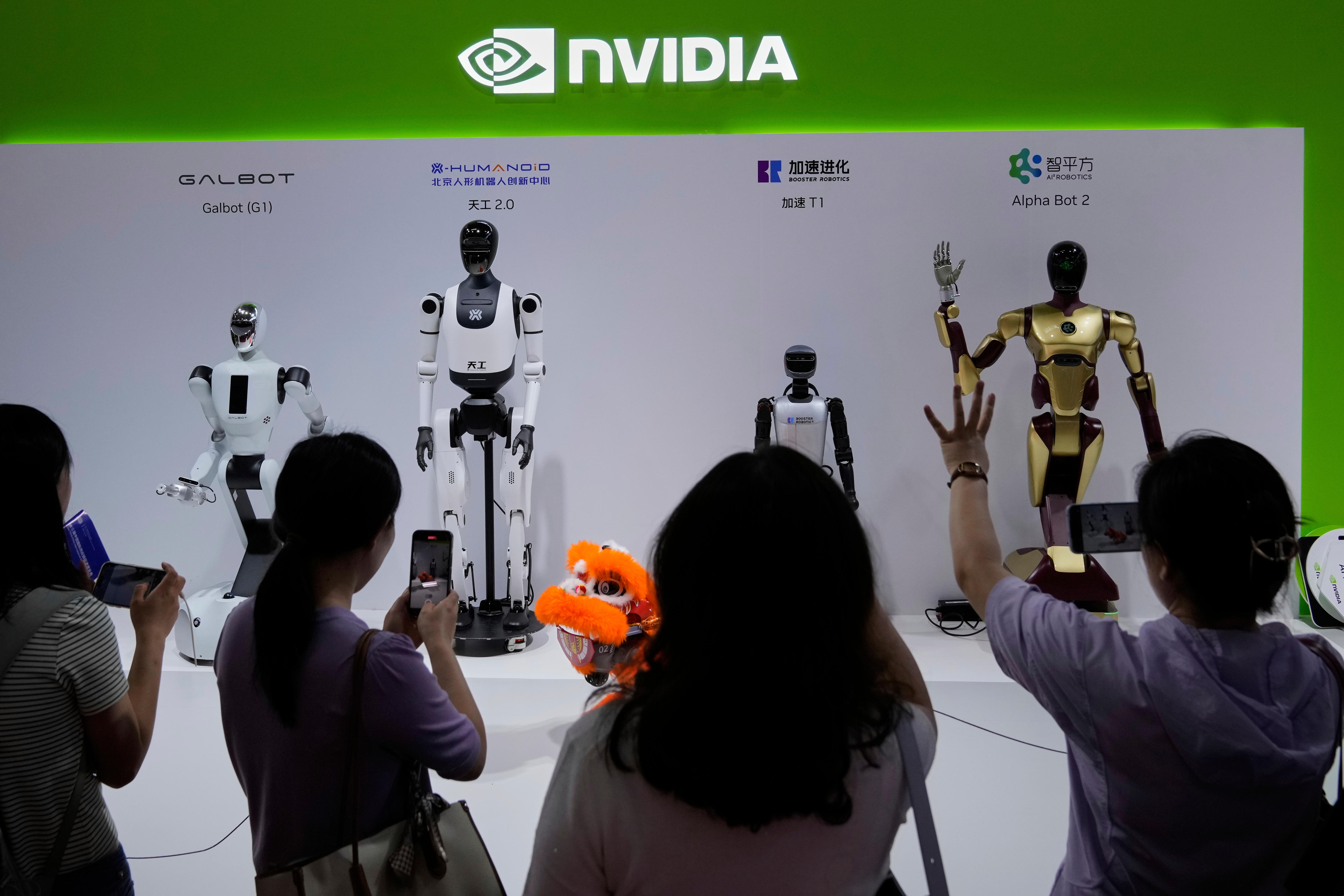 Four robots stand on a white stand on show in front of people taking photos of them