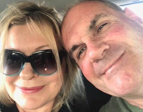 Two people smiling for the camera, one of whom is wearing sunglasses.