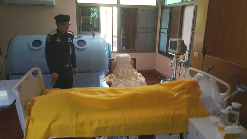 Thai police examine Phra Dhammachayo's bed before the blankets are pulled back to reveal there is no-one there.