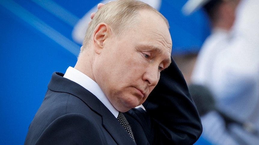 Vladimir Putin looking pensive while running his hands through his hair 