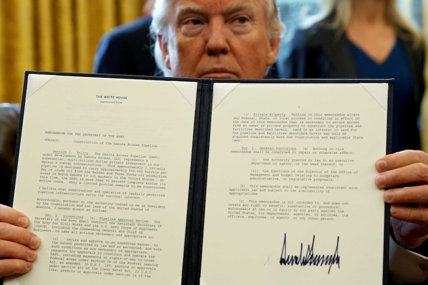 Donald Trump holds up a signed executive order