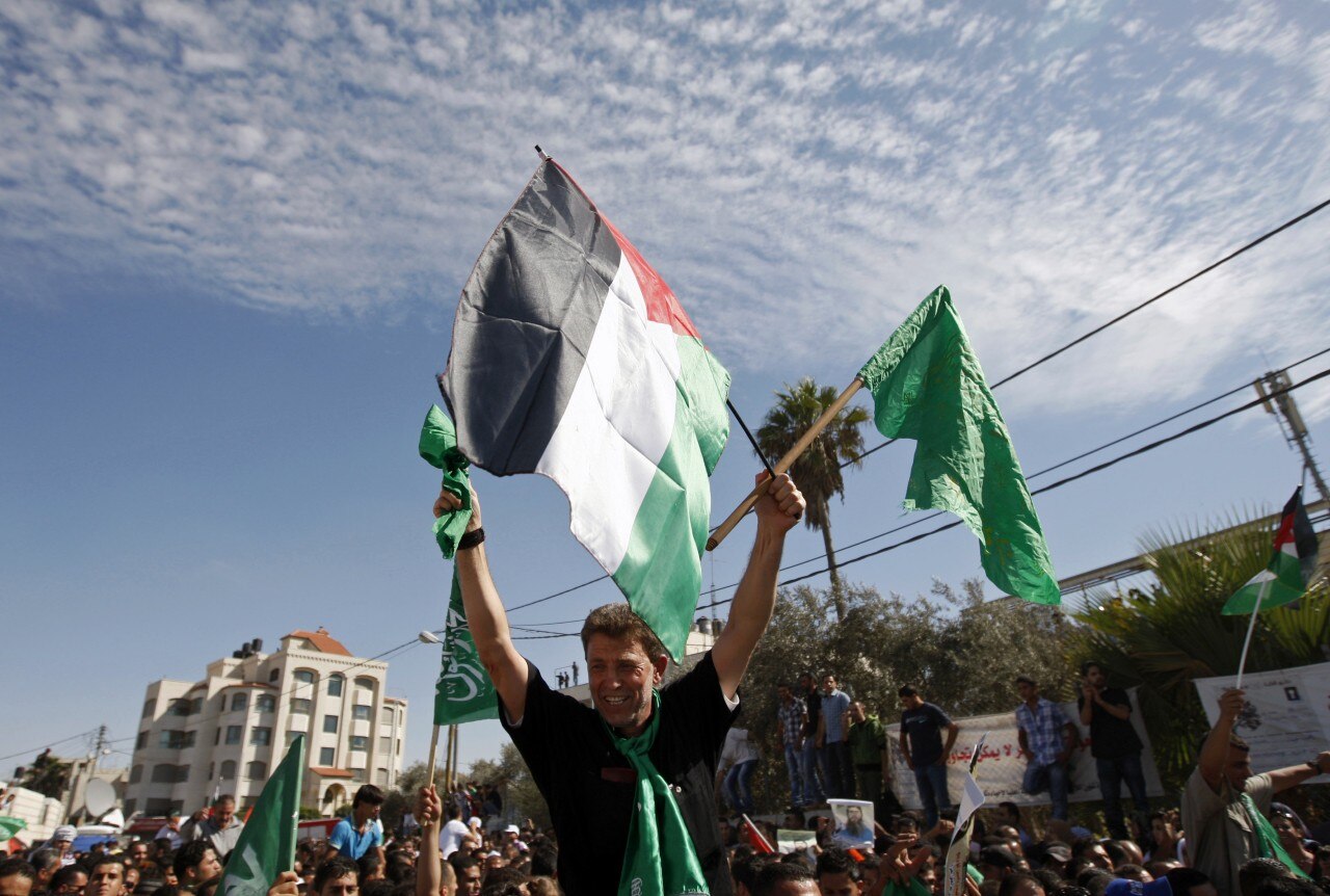 A man waving flags while sitting on another man's shoulders.