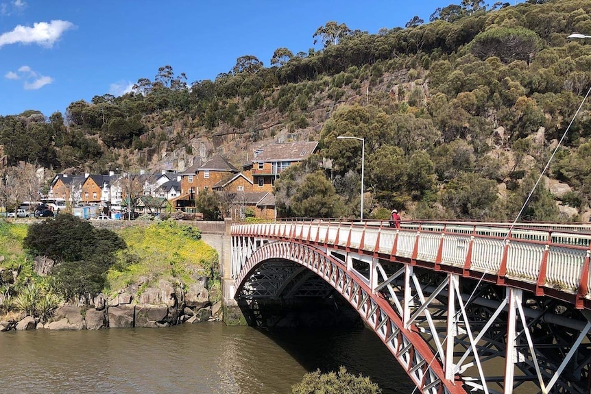 Historic steel bridge over a river, looking towards stone buildings on the other side of the river