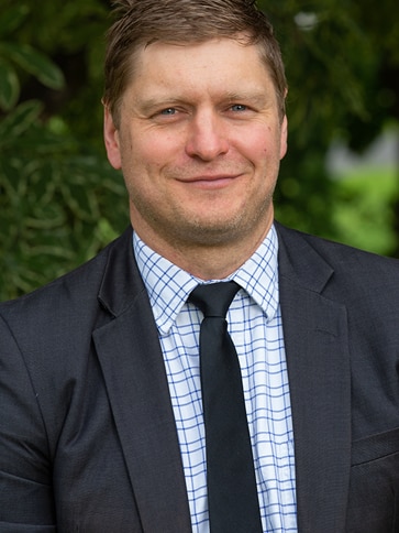 A man in a suit smiles.