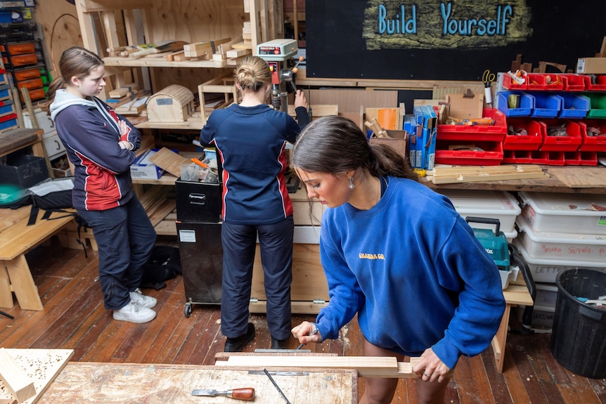 Girls in a woodworking program space working