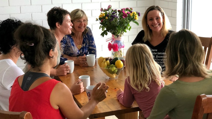 Women sit around a table talking about anti-vaccination