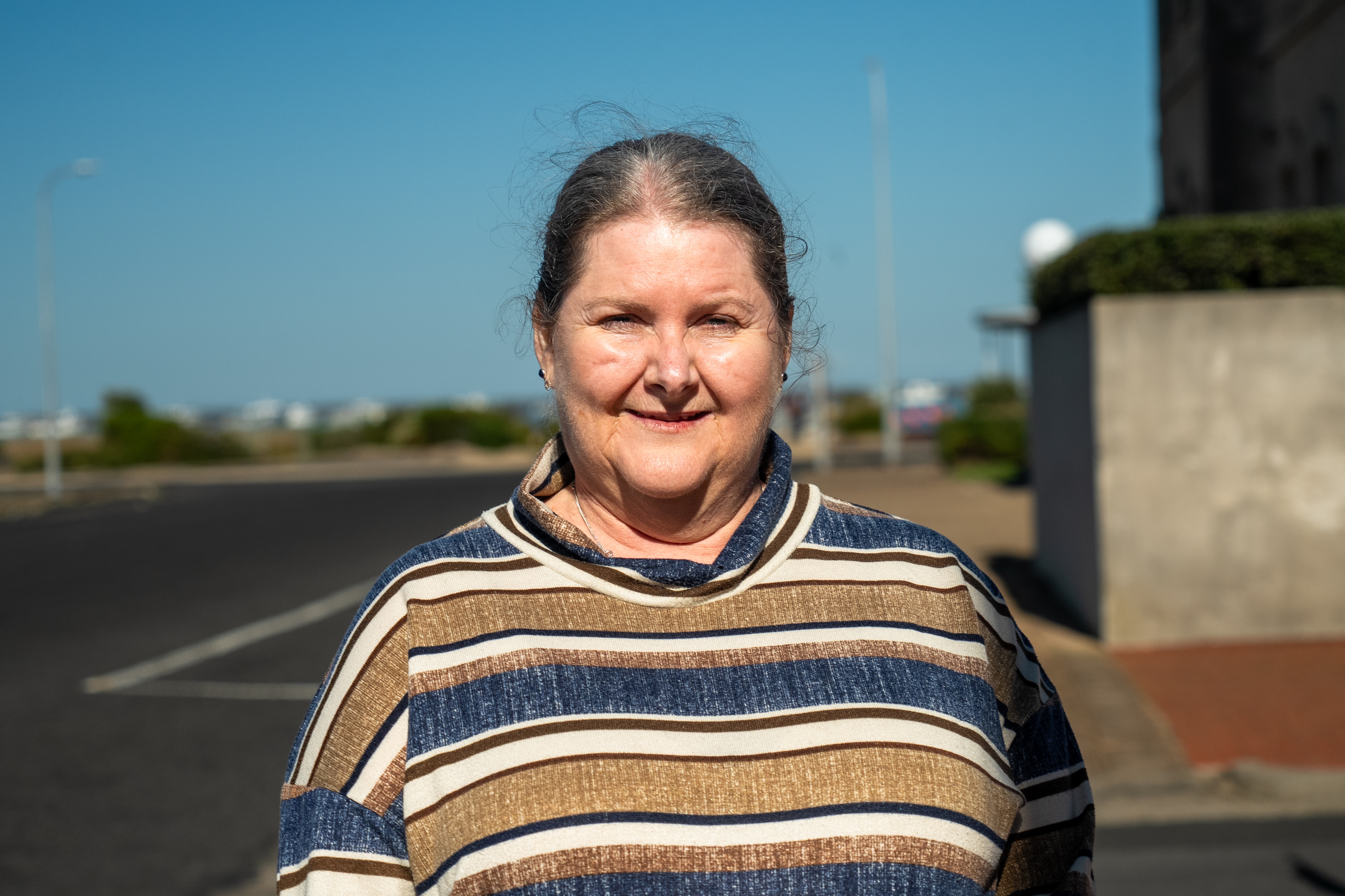 A woman wearing a striped jumper looks to camera with a slight smile.