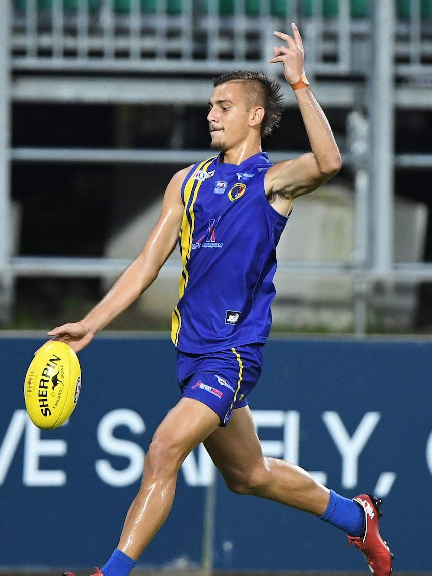 Joel Jeffrey, wearing blue and yellow, kicks for goal in the AFLNT.