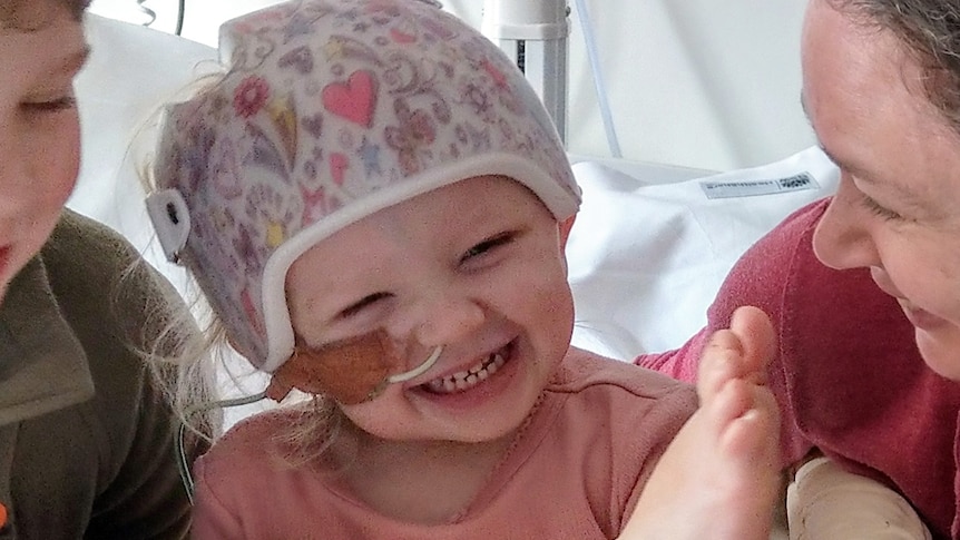 A young toddler laughing in a pink helmet