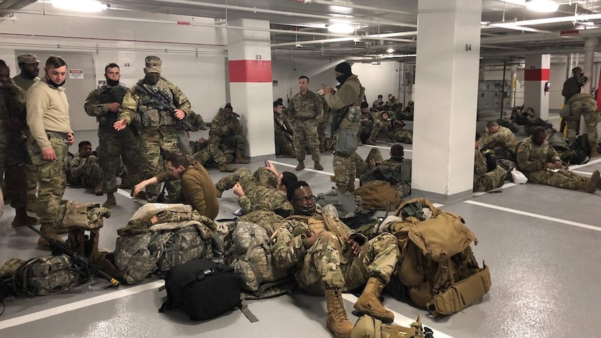 national guard troops in camouflage uniform stand and laying down in an underground car park