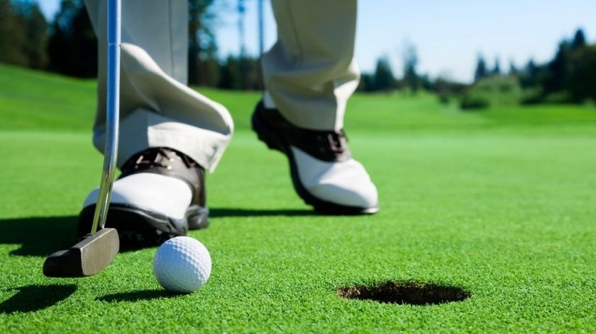 A golf ball sits on the edge of a hole