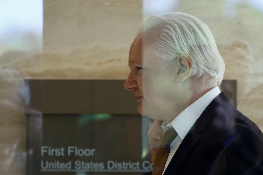 Julian Assange smiles as he enters court 