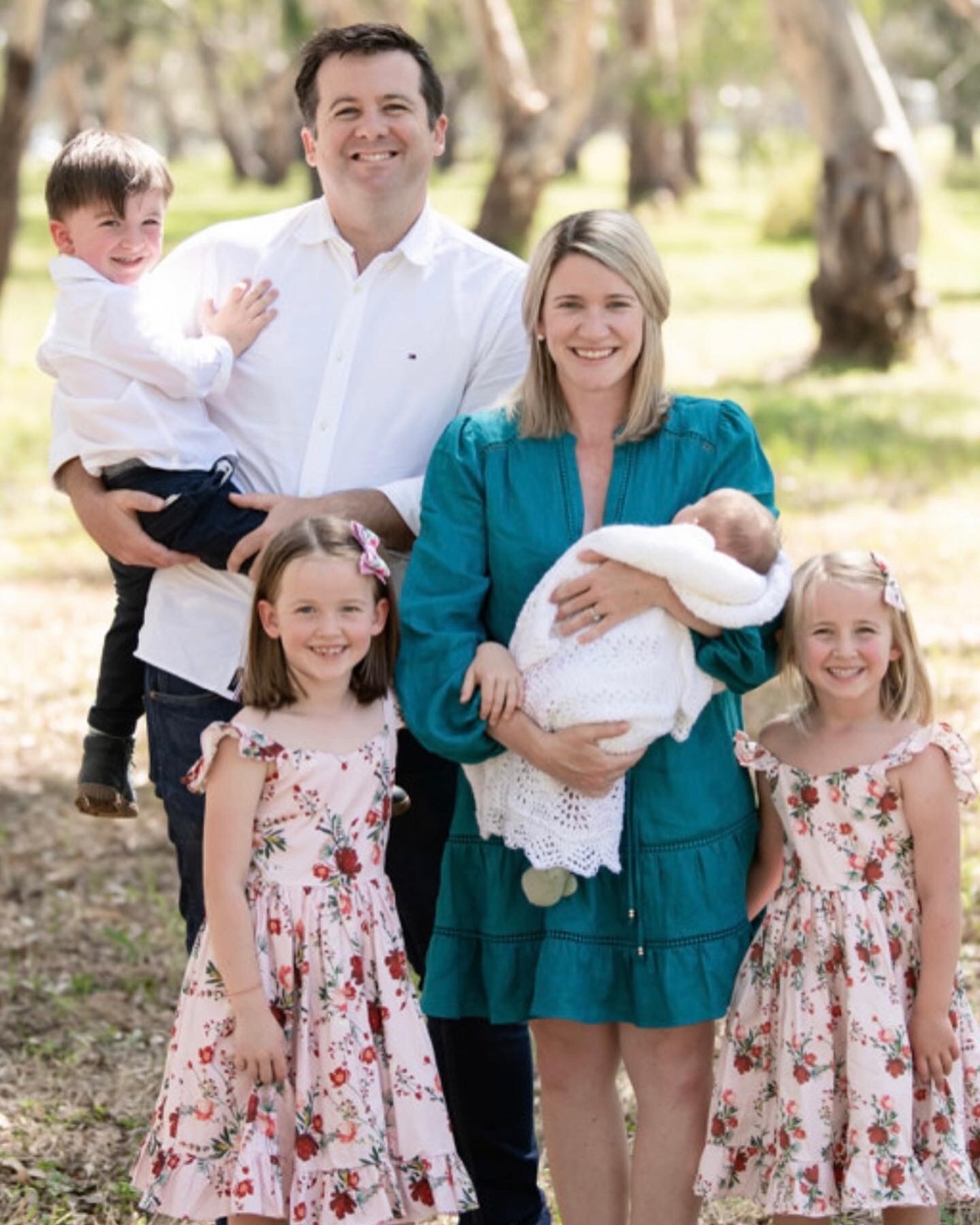 A mother and father take a photo with their four young children