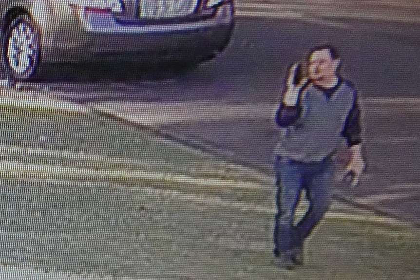 a CCTV still image of a man holding a mobile phone